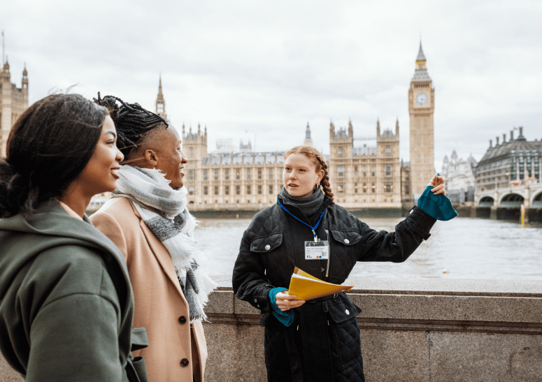 A tour guide with tourists beside the London bridge